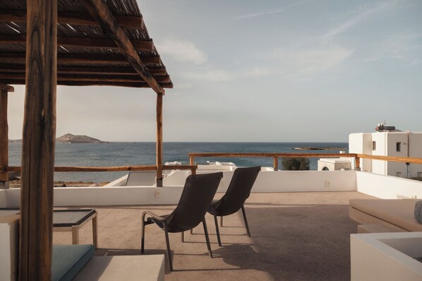 A rooftop terrace with two chairs, a table, and a view of the sea and a distant island. - Siora of Paros - Malatesta & Piccolo (Paros)