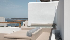 Eine Dachterrasse mit Whirlpool, Sitzgelegenheit und Meerblick.