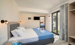 A modern hotel room with a large bed, a television, and a sliding glass door to the balcony. - Pnoe Beachside Suite (Georgioupoli)