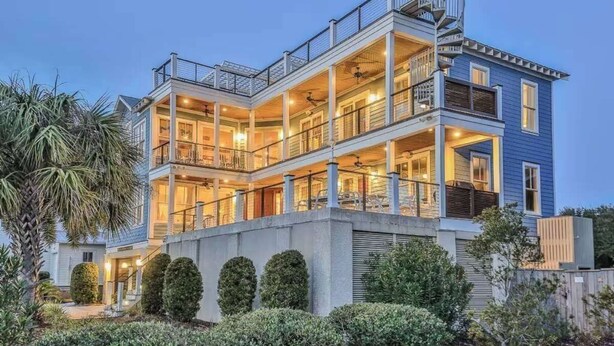 A multi-story house with a balcony, a spiral staircase, and a well-lit interior. - Beautiful Family Home with Private Pool, Hot Tub Movie Room & Rooftop Terrace! Ocean Views, Beach steps away! (Isle of Palms)