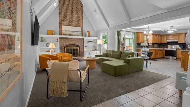 A spacious living area with a fireplace, a green sofa, and a dining table. - NEW: Big House, 13 beds, 6 bedroom, 17 min to DT (Overland Park)