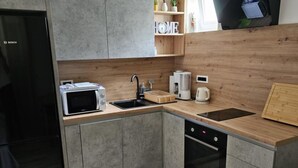 Een kleine keuken met een magnetron, koffiezetapparaat en vaatwasser.