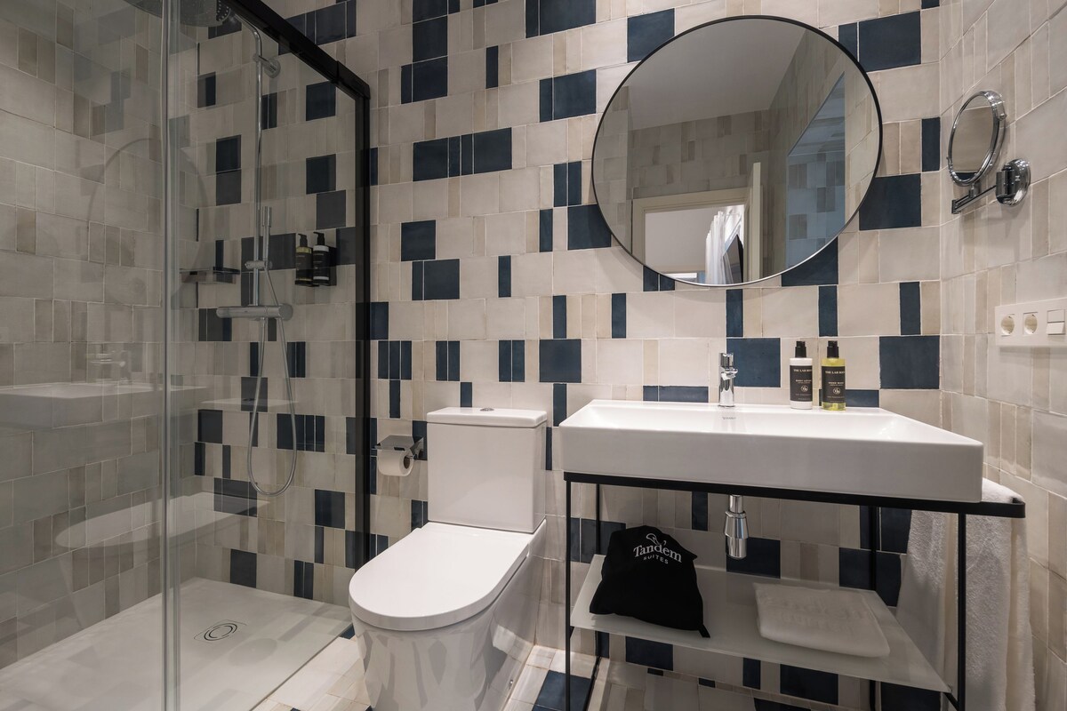 Een moderne badkamer met een douchecabine van glas, een wit toilet en een wastafel met een spiegel erboven.