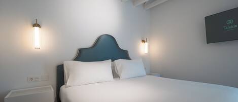 Ein modernes Hotelzimmer mit einem ordentlich bezogenen Bett, zwei Nachttischen und einem an der Wand befestigten Schild für Tandet Suites.