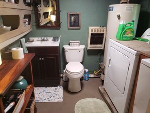 A compact bathroom with a toilet, sink, and a washing machine. - This unique property is a perfect place to relax and unwind. (Fayetteville)