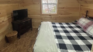 A cozy attic bedroom with a bed, a television, and a window. - Secluded Mountaineee -View Cabin with Hot Tub & Endless Country Sky (Elgin)
