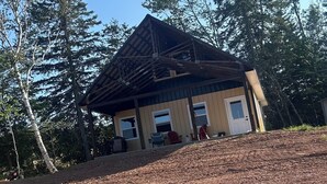 A cabin with a wooden exterior, a pitched roof, and a front porch. - Secluded Mountaineee -View Cabin with Hot Tub & Endless Country Sky (Elgin)