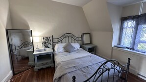 Un dormitorio con cama, mesitas de noche, un espejo y ventana.