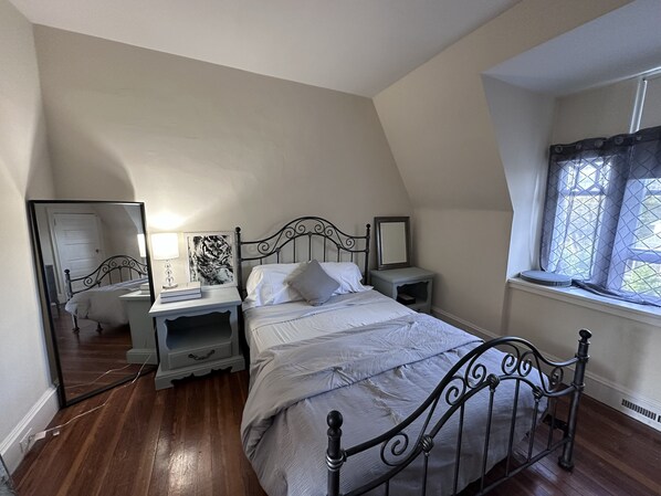 A bedroom with a bed, bedside tables, a mirror, and a window.