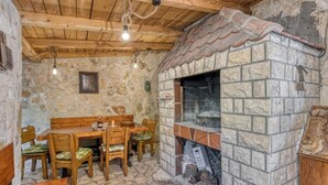 Un intérieur rustique avec des murs en pierre, une table et des chaises en bois, une cheminée en pierre et un plafond en bois.