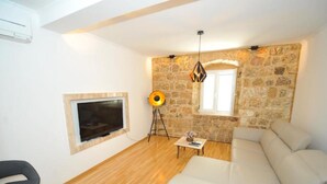 Una sala de estar con pared de piedra, un sofá, un televisor, una lámpara y un sillón.