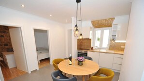 Una cocina compacta con armarios blancos, una mesa de madera y dos sillas.
