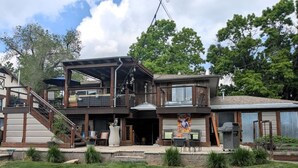 A two-story house with a covered patio, outdoor seating, and a large window. - Luxurious Littleton Living with Gourmet Kitchen, Huge Deck and Shared Backyard (Littleton)