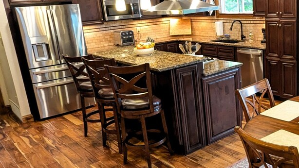 A modern kitchen with dark wood cabinets, stainless steel appliances, and a granite countertop. - Luxurious Littleton Living with Gourmet Kitchen, Huge Deck and Shared Backyard (Littleton)