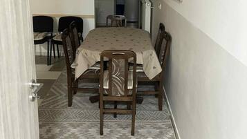 A dining area with a table, chairs, and a kitchen in the background.