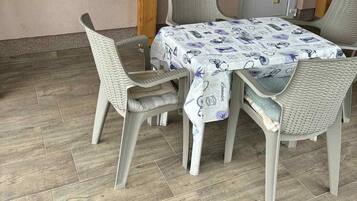 Ein Essbereich mit Korbstühlen und einem Tisch, bedeckt mit einer gemusterten Tischdecke.