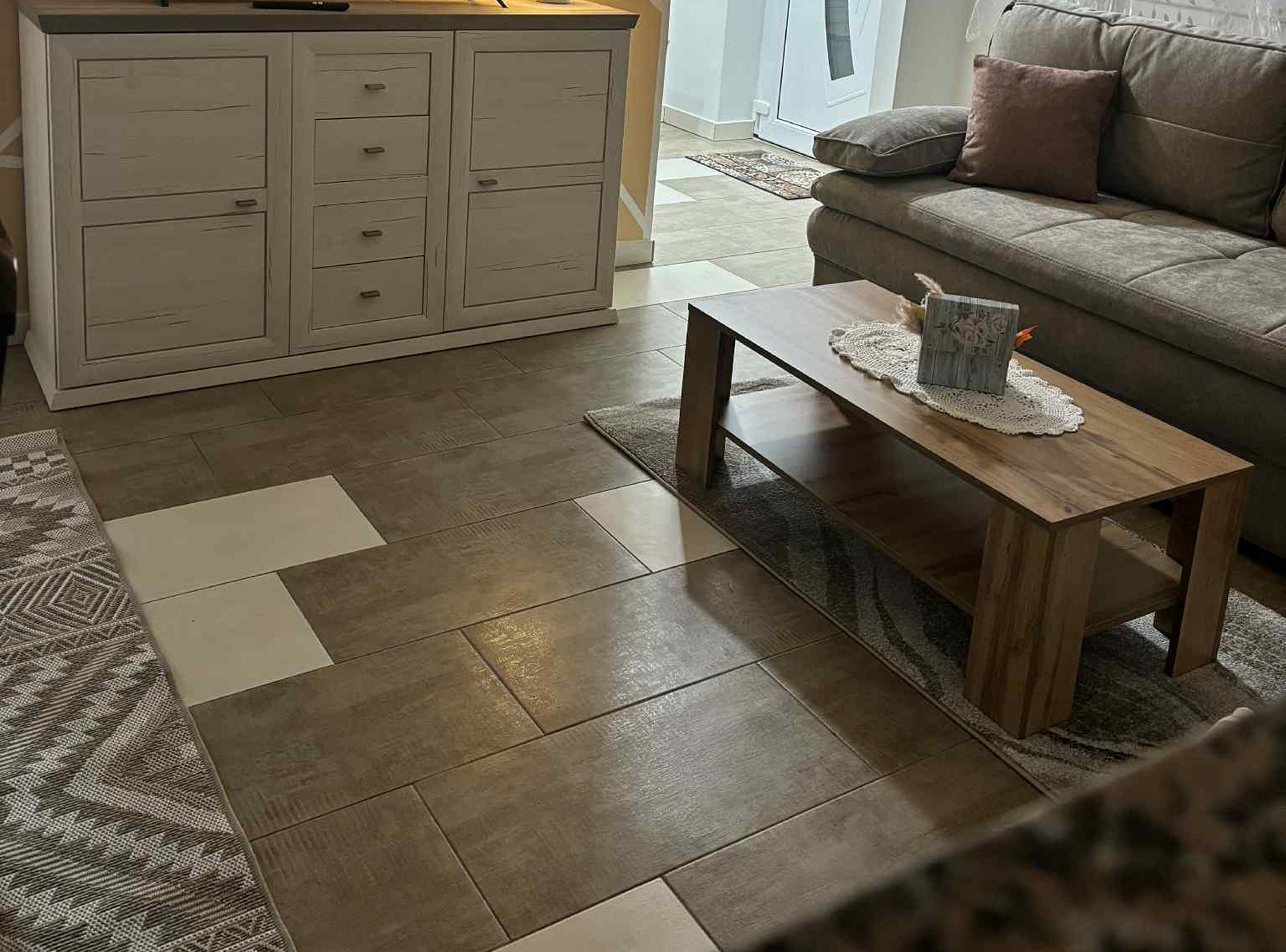 Una sala de estar con un sofá, una mesa de centro de madera y una zona de cocina con armarios.