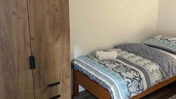 Un dormitorio con un armario de madera, una cama con ropa de cama estampada y un pequeño estante en la pared.