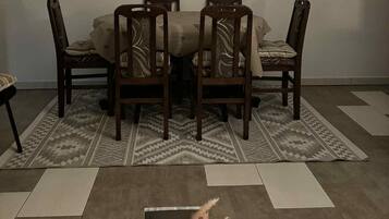 Un comedor con una mesa y cuatro sillas, un tapete estampado y una mesa de centro de madera con objetos decorativos.