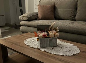 A living room with a wooden coffee table, a box of decorative items, and a grey sofa. - Comfort Apartment Luna (Varazdin)