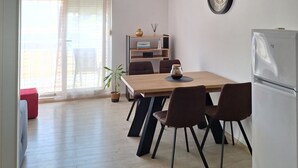 Una cocina moderna con una mesa de comedor de madera, sillas negras, un refrigerador y una planta en maceta.
