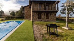 Un edificio de piedra con piscina, zona de barbacoa y vistas al paisaje.