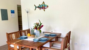Una mesa de comedor de madera con platos azules y un florero, en una habitación con suelo de madera y pared blanca.