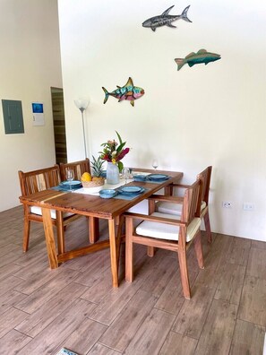 Ein Holzesstisch mit blauen Tellern und einer Blumenvase, in einem Raum mit Holzboden und weißer Wand.