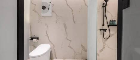 A modern bathroom with a toilet, a shower with a handheld showerhead, and a marble-patterned wall.