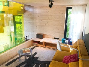 Una habitación acogedora estilo cabaña con interior de madera, un sofá, una mesita y una ventana con cortinas.