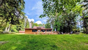 A wooden cabin with a deck, surrounded by a grassy area and trees. - Secluded 8 acre lakefront resort on Grand Portage Lake. (Mercer)
