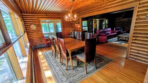 A log cabin interior with a dining area, wooden floors, and a chandelier. - Secluded 8 acre lakefront resort on Grand Portage Lake. (Mercer)