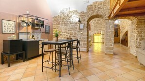 A kitchen with a stone wall, a dining area with a table and chairs, and a staircase leading to another level. - Luxury House 'Apulia' with Wi-Fi (Toritto)