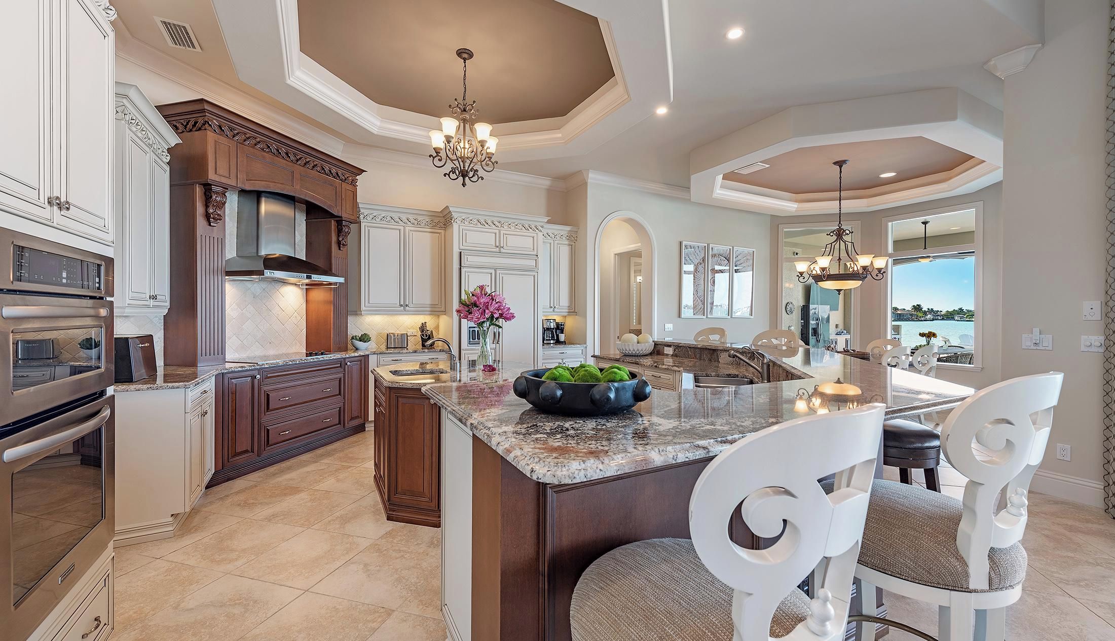 A spacious kitchen with a large island, built-in appliances, and a view to the outside.