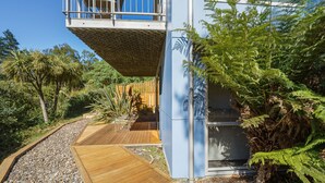 A modern house with a wooden deck, a balcony, and lush greenery. - Harbour Crest Retreat - Lyttelton Holiday Home (Lyttelton)