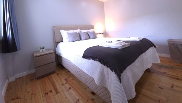 Une chambre à coucher avec un lit, des tables de chevet, une lampe et une poubelle.