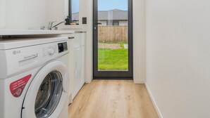 Ein kleiner Waschraum mit Waschmaschine, Spüle und Fenster.