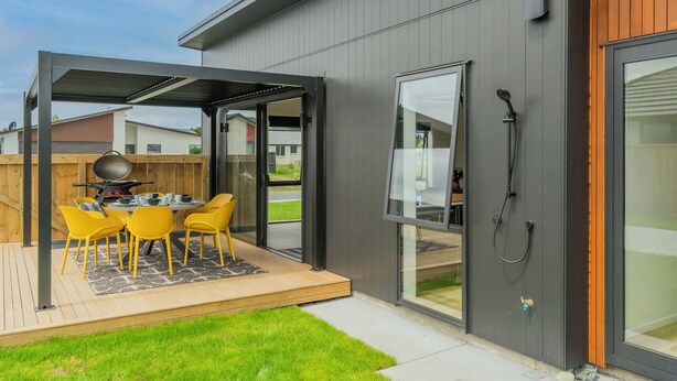 Eine moderne Terrassenanlage im Freien mit Grill, gelben Stühlen und einer Holzterrasse.
