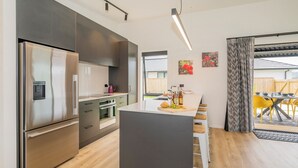 Eine moderne Küche mit Edelstahlgeräten, einer zentralen Kochinsel und einem Essbereich mit gelben Stühlen.