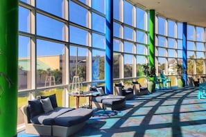 A spacious indoor area with large windows, outdoor seating, and a patterned floor. - Splash! Kids Aqua park, Free rental chairs! (Panama City Beach)