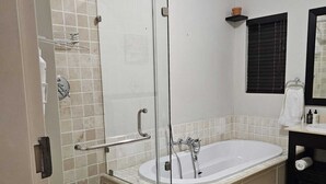 Ein modernes Badezimmer mit einer Duschkabine aus Glas, einer freistehenden Badewanne und einem schwarzen Waschtisch mit Spiegel.