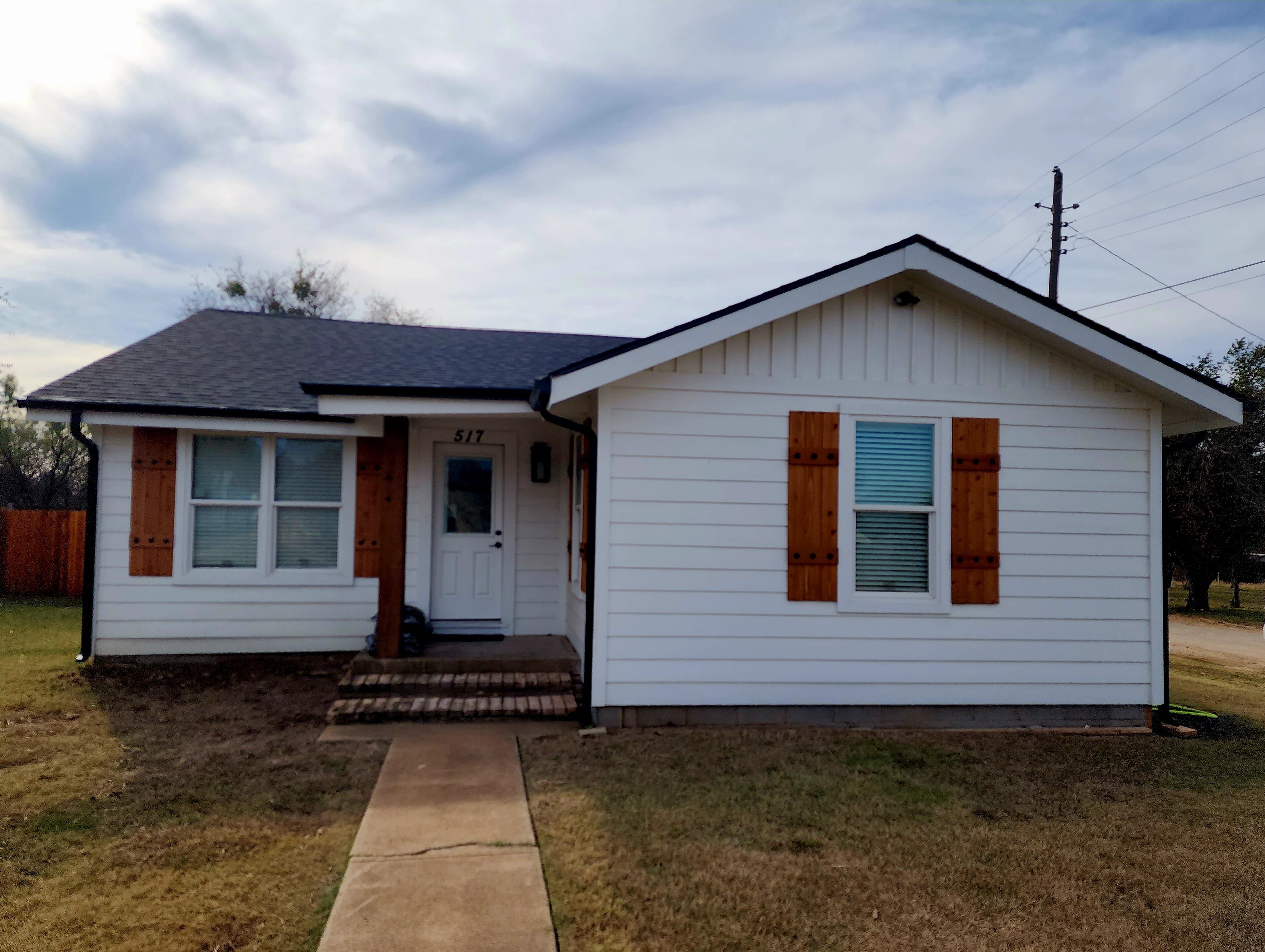 A small, single-story house with a white exterior, a dark roof, and a number '517' on the front door.