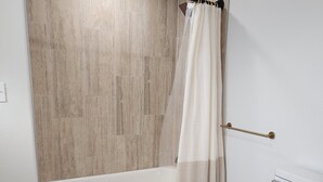 Een badkamer met een bad, toilet en douchegordijn.