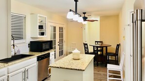 A compact kitchen with white cabinets, a built-in microwave, and a granite countertop. - Family Retreat Near Kalahari-Sleeps 11 (Round Rock)