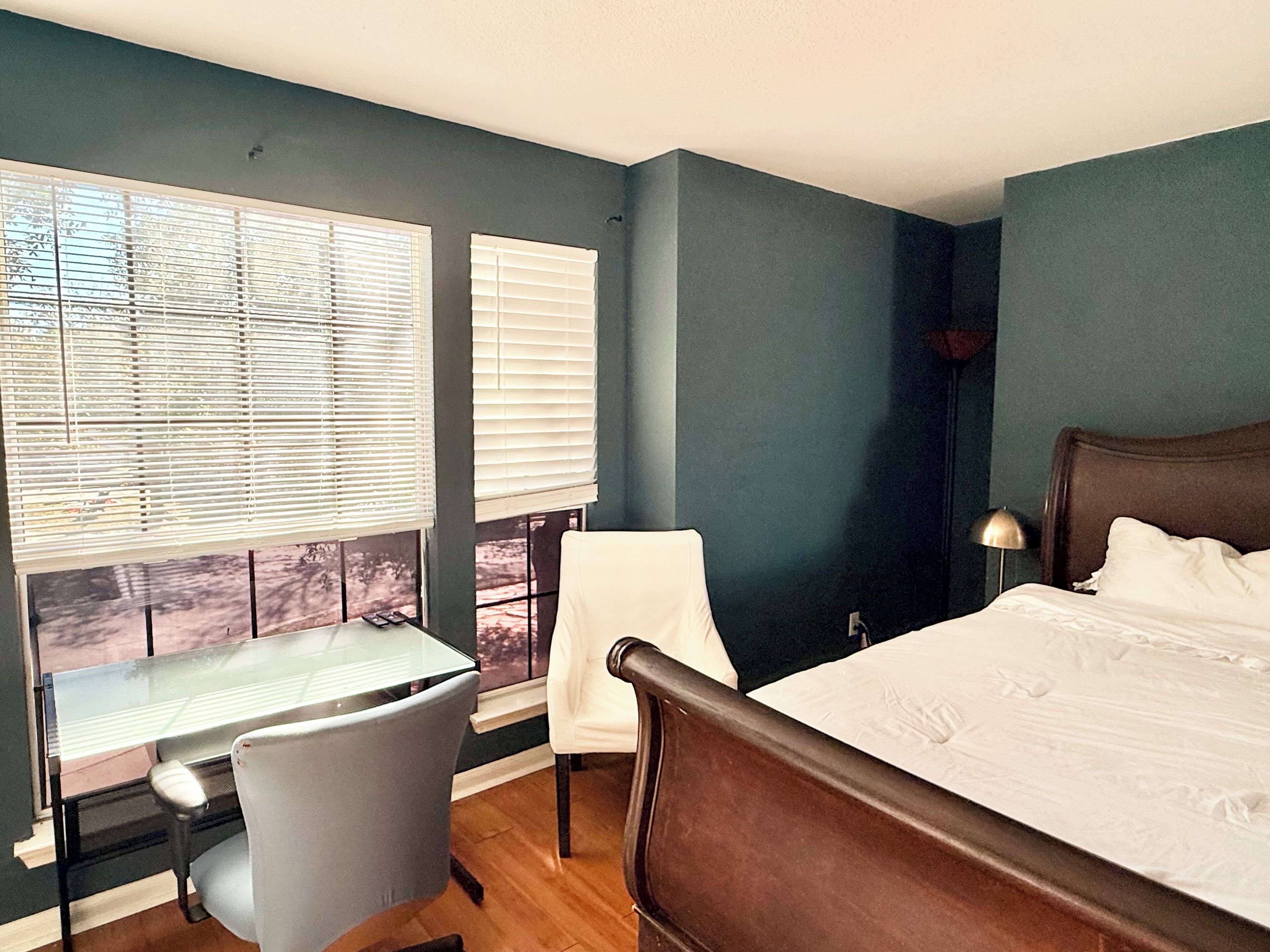 A bedroom with a bed, a desk, and a chair.