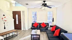 A living room with a black leather sofa, a coffee table, a ping pong table, and a staircase with a decorative wall. - Family Retreat Near Kalahari-Sleeps 11 (Round Rock)