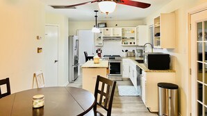 A compact kitchen with white cabinets, a stove, a refrigerator, and a ceiling fan. - Family Retreat Near Kalahari-Sleeps 11 (Round Rock)