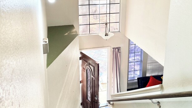 A staircase with a handrail, a hanging light fixture, and a door leading to an outdoor area. - Family Retreat Near Kalahari-Sleeps 11 (Round Rock)