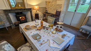Zona pranzo con tavolo apparecchiato per un pasto, un caminetto e vista sull'esterno.