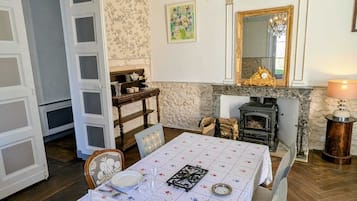 Une salle à manger avec un lustre, une cheminée et un miroir au mur.